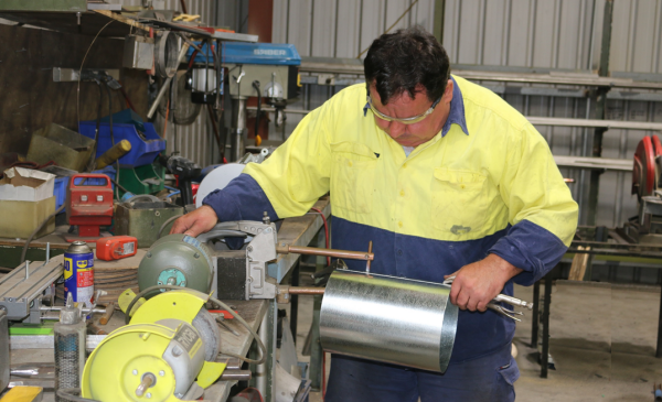 Man in a warehouse making a vent cowl